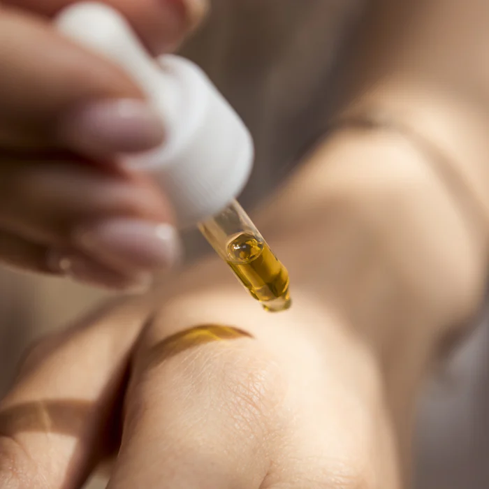 A drop of golden massage oil falling from a glass dropper